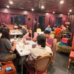 Game night upstairs at The Wicked Wolf. several tables, surrounded by young guests playing various games.