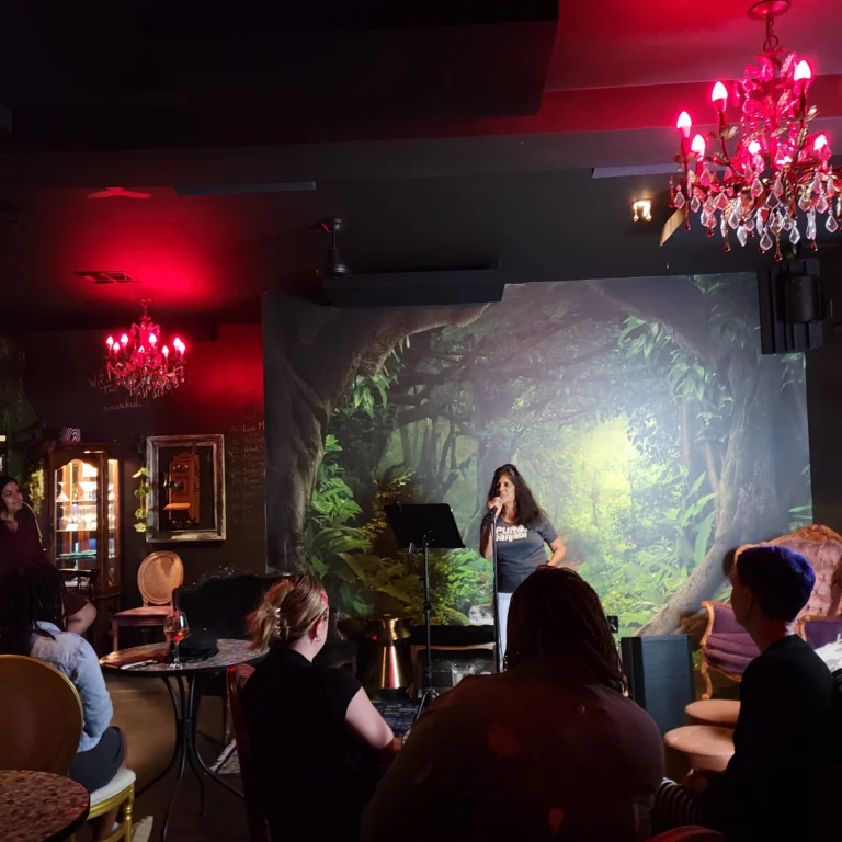 Woman in blue shirt reads poem at Muse on fire